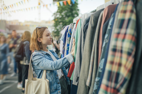 Una giovane cerca abiti di seconda mano in un mercato foto iStock.