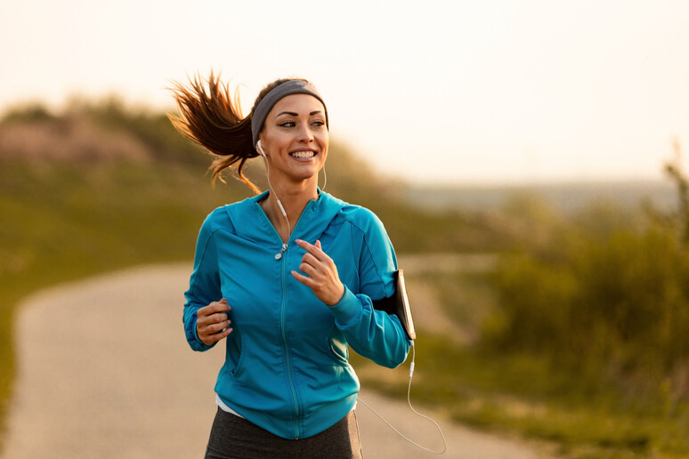 Happy female runner jogging in the morning in nature. - RIPRODUZIONE RISERVATA