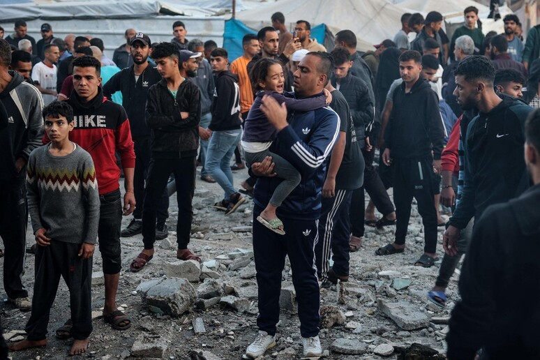 Homem segura criança chorando após ataque israelense contra escola em Gaza © ANSA/AFP