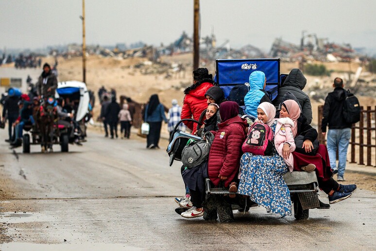 Palestinos na parte de trás de um carrinho de triciclo entre a Cidade de Gaza e Nuseirat © ANSA/AFP